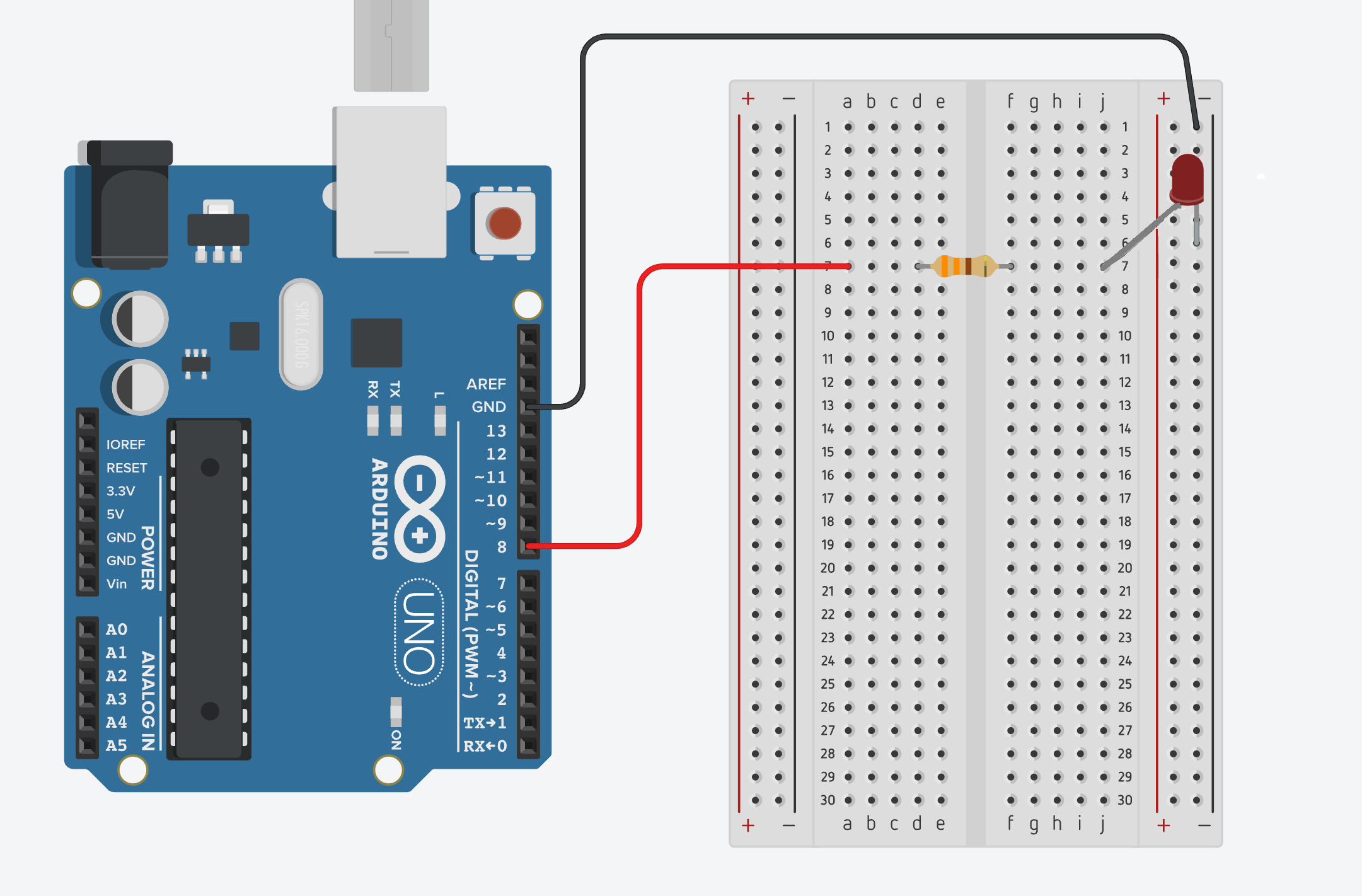 Arduino UNO positioned beside a solderless breadboard on a mounting board